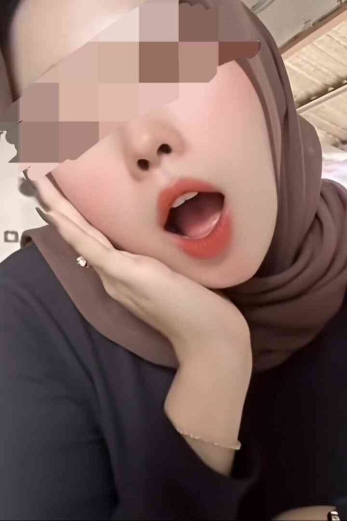 Zana, a 22yo Malaysian beauty, wearing a hijab and a black top, with her mouth open.