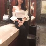 KL escort call girl smiling in a white off-the-shoulder top and black pants