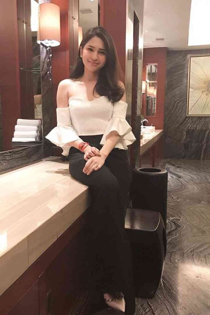 KL escort call girl smiling in a white off-the-shoulder top and black pants